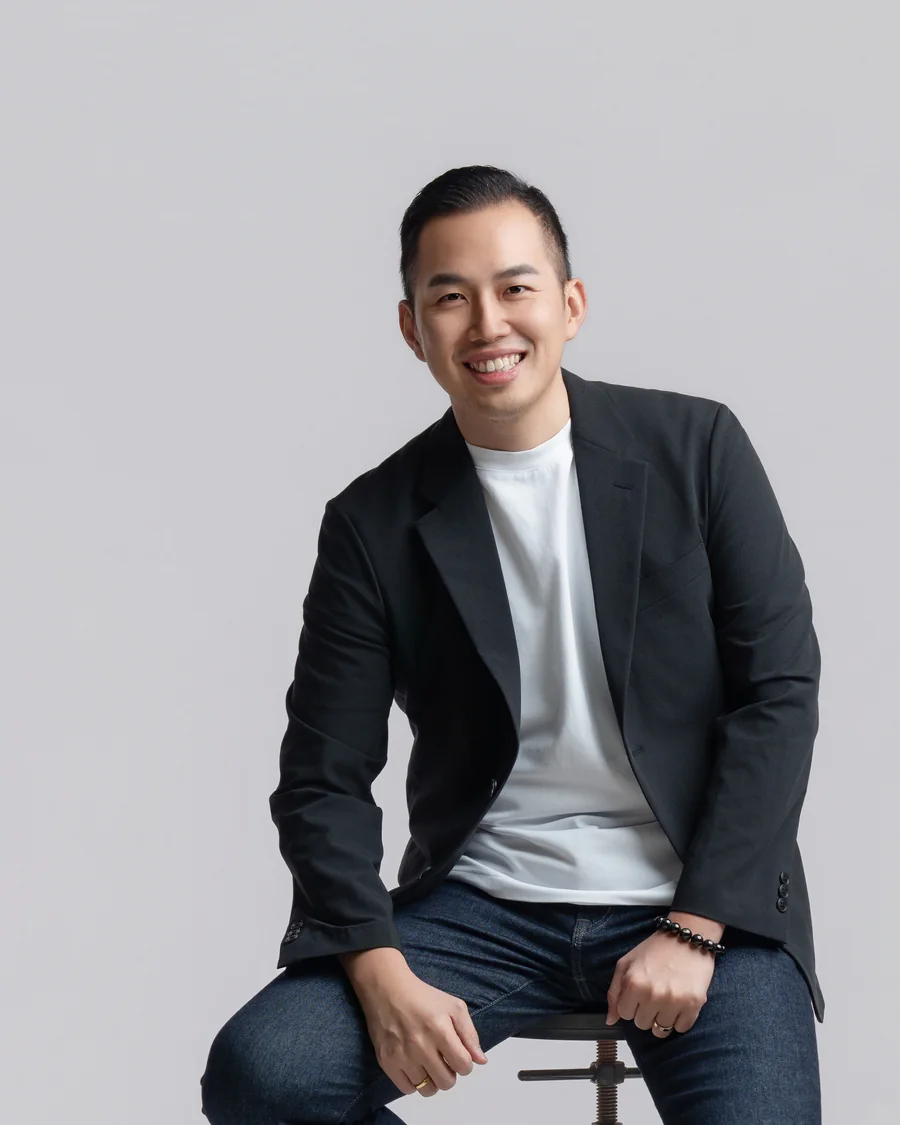 Simon 巫，黑西裝外套白 T 恤，坐在高腳椅上微笑